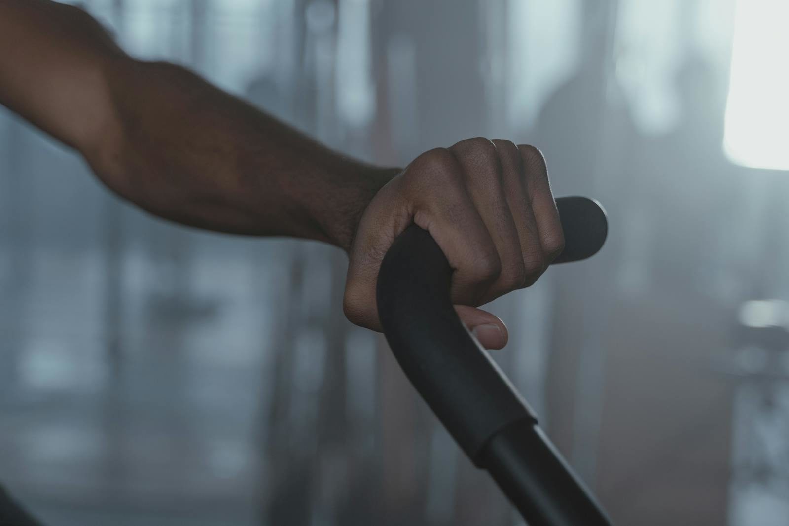 Focused shot of a person's hand firmly gripping gym equipment indoors.